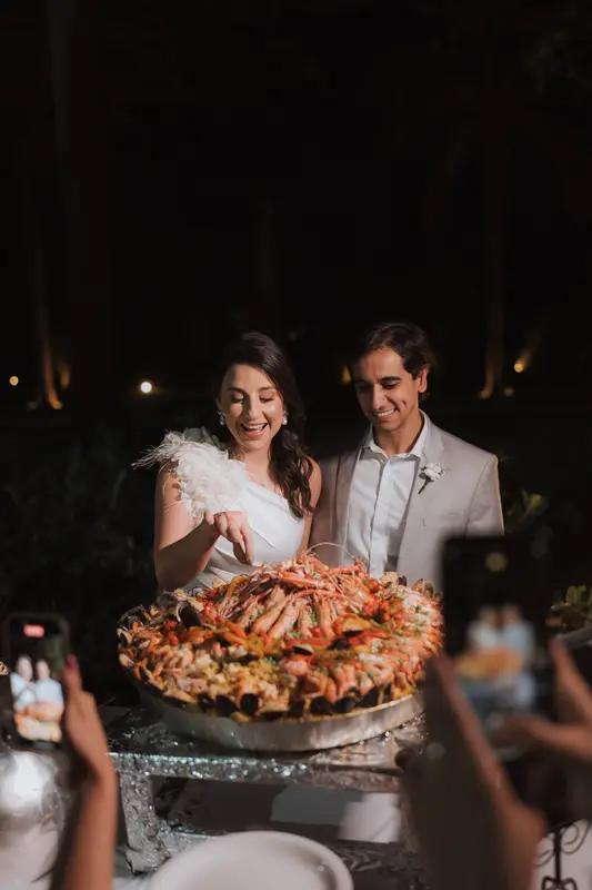 Noivos ao lado da paella servida no casamento